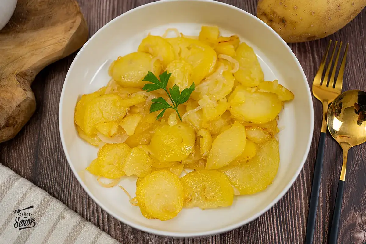 Un plato de patatas panaderas doradas y tiernas, con cebolla caramelizada y un toque de perejil. ¡Un clásico delicioso!