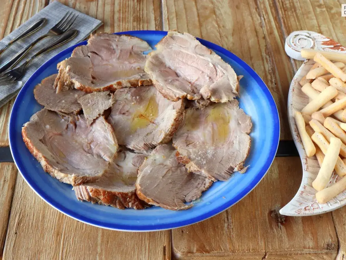 Plato azul con lonchas de jugosa carne mechada, servida con palitos de pan crujientes a un lado.