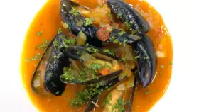 Mejillones a la marinera, jugosos y frescos, nadan en una salsa roja vibrante con perejil picado.