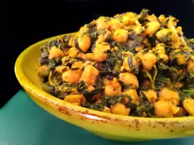 Un plato amarillo lleno de garbanzos con espinacas, un guiso saludable y sabroso.