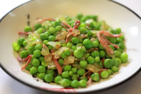 Guisantes con jamón, un plato sencillo y delicioso. Los guisantes frescos se mezclan con trocitos de jamón y cebolla salteada, creando un bocado lleno de sabor.
