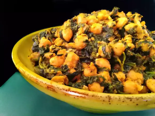 Un plato amarillo lleno de garbanzos con espinacas, un guiso saludable y sabroso.