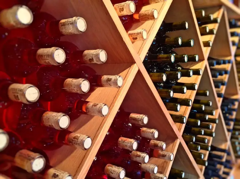 Estanterías de madera llenas de botellas de vino tinto y blanco. Un lugar donde se guarda el vino, listo para ser disfrutado.